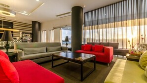 A modern living room with a grey sofa, a red sofa, and a green sofa. There is a coffee table in the center. - YIT Via Sevilla Mairena (Mairena del Aljarafe)