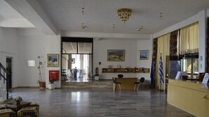 A spacious lobby with a reception desk, chairs, and a staircase leading to another area. - Lymiatis Beach Hotel (Karpathos)