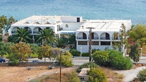 A white building with multiple balconies and solar panels, located near a beach. - Lymiatis Beach Hotel (Karpathos)