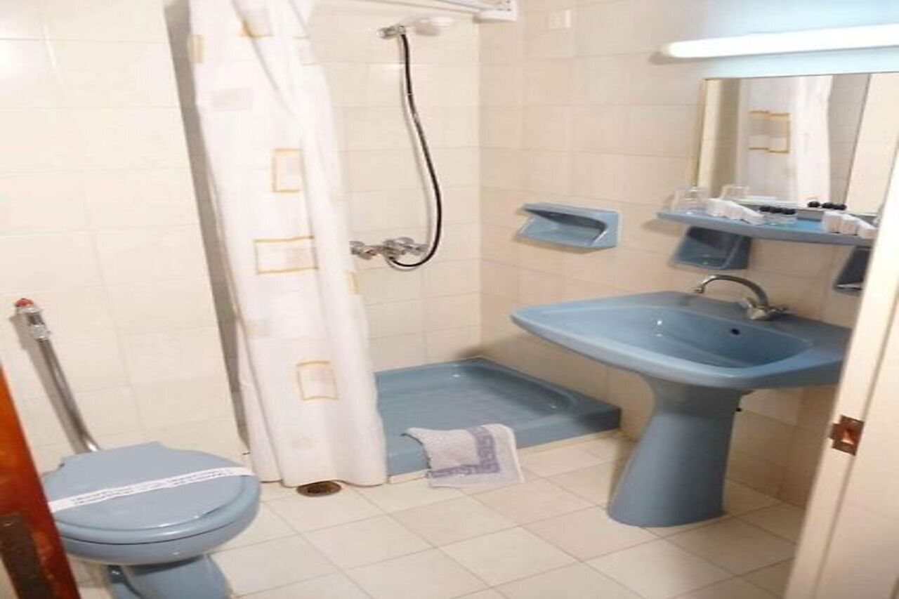 A bathroom with a toilet, shower, and sink.
