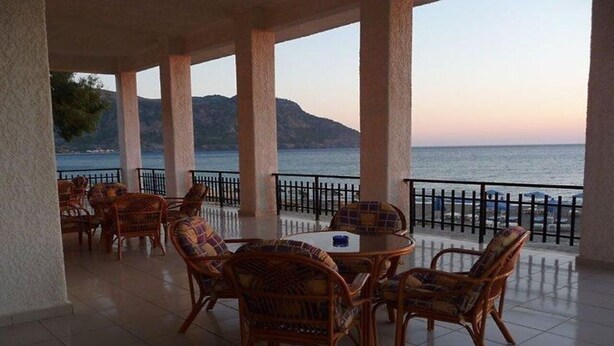 A covered outdoor seating area with wicker furniture and a view of the sea. - Lymiatis Beach Hotel (Karpathos)