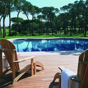 A wooden deck with a swimming pool, surrounded by trees. - Nuevo Portil Golf (Cartaya)