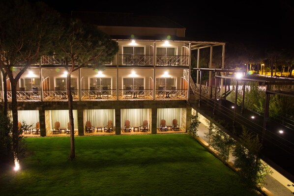 A multi-story hotel with outdoor seating areas and a well-lit balcony. - Nuevo Portil Golf (Cartaya)