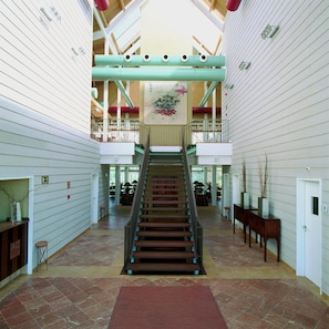 A spacious interior with a central staircase, high ceilings, and a mezzanine level. - Nuevo Portil Golf (Cartaya)