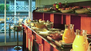 A breakfast buffet with various dishes and drinks, a glass pitcher of orange juice, and a view of a building outside. - Nuevo Portil Golf (Cartaya)