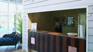 A reception desk with a sign reading "AC" and a framed picture on the wall. - Nuevo Portil Golf (Cartaya)