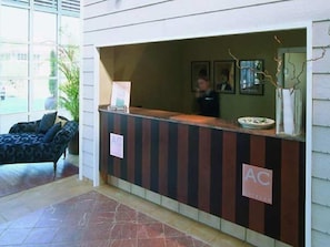 A reception desk with a sign reading "AC" and a framed picture on the wall. - Nuevo Portil Golf (Cartaya)