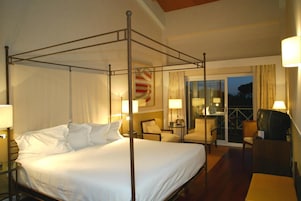 Una cama con dosel en una habitación de hotel con balcón y televisión.