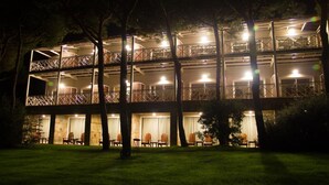 A multi-story hotel with balconies, outdoor seating, and a well-lit facade at night. - Nuevo Portil Golf (Cartaya)