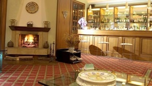 A bar area with a fireplace, bar stools, and a variety of bottles. - Meditur Hotel Bologna (San Lazzaro di Savena)