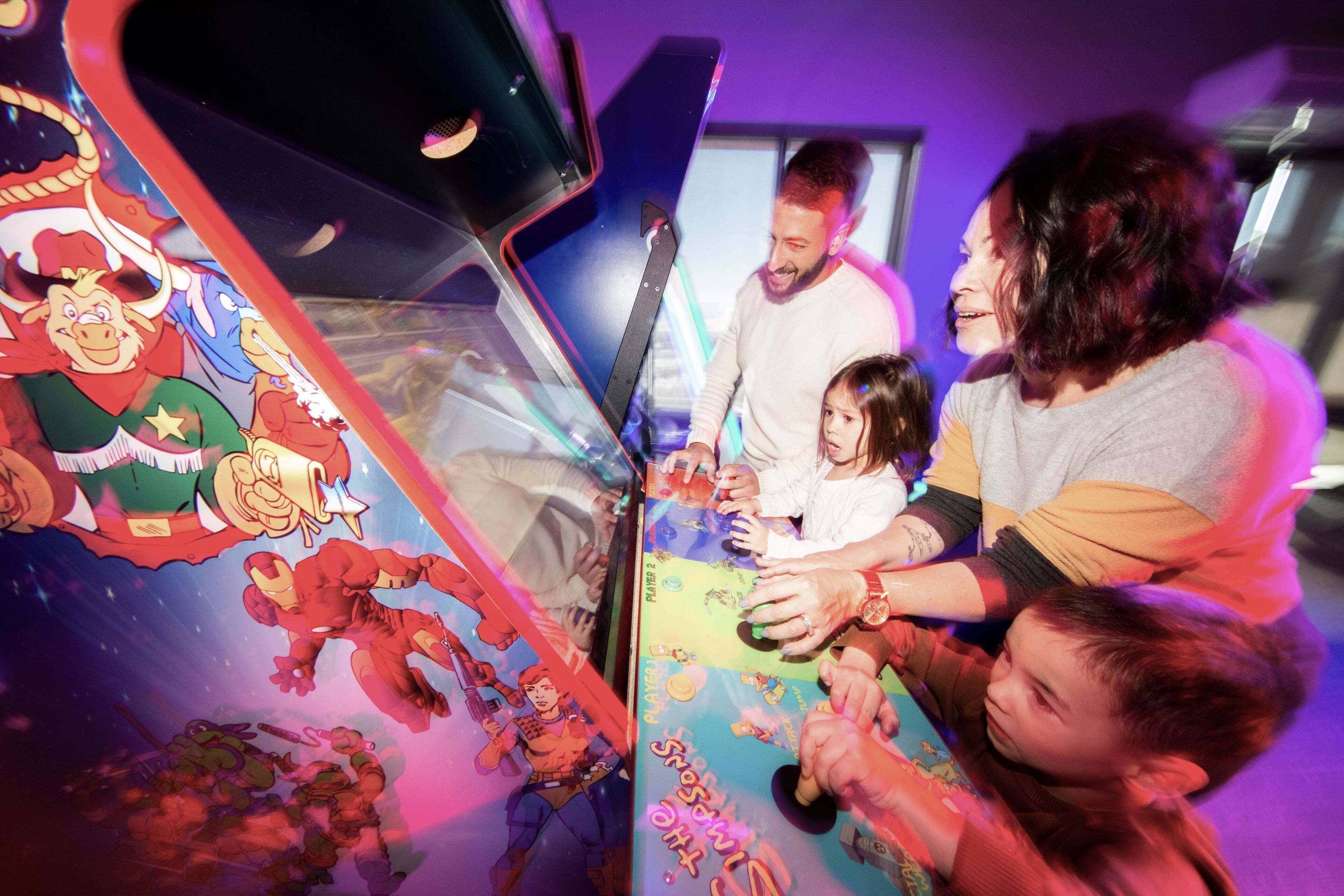 A family interacting with a colorful, interactive display featuring cartoon characters.