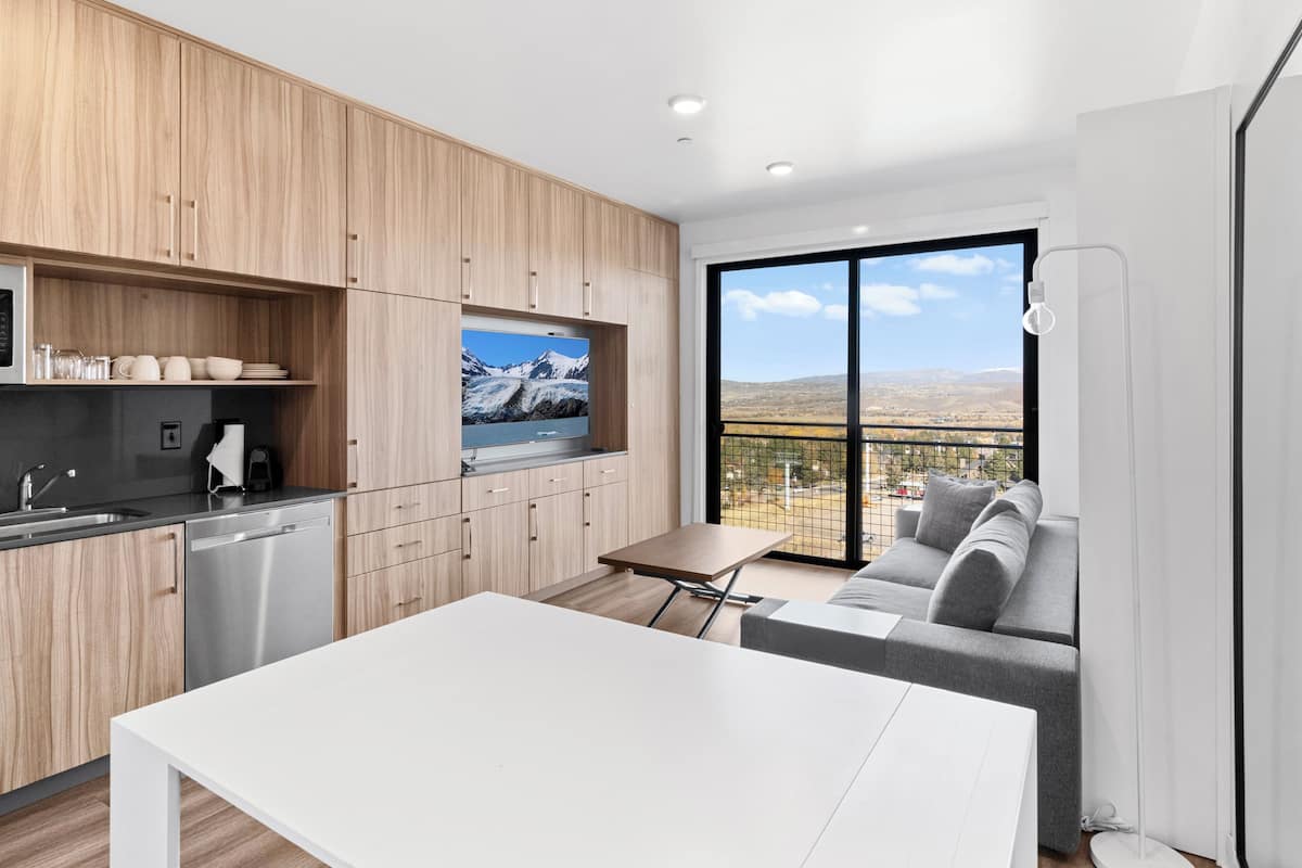 Une cuisine moderne avec des meubles en bois, un lave-vaisselle en acier inoxydable et une grande fenêtre offrant une vue panoramique.