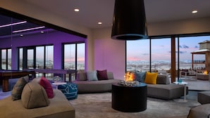 A modern living room with a fireplace, large windows, and a view of a snowy landscape.