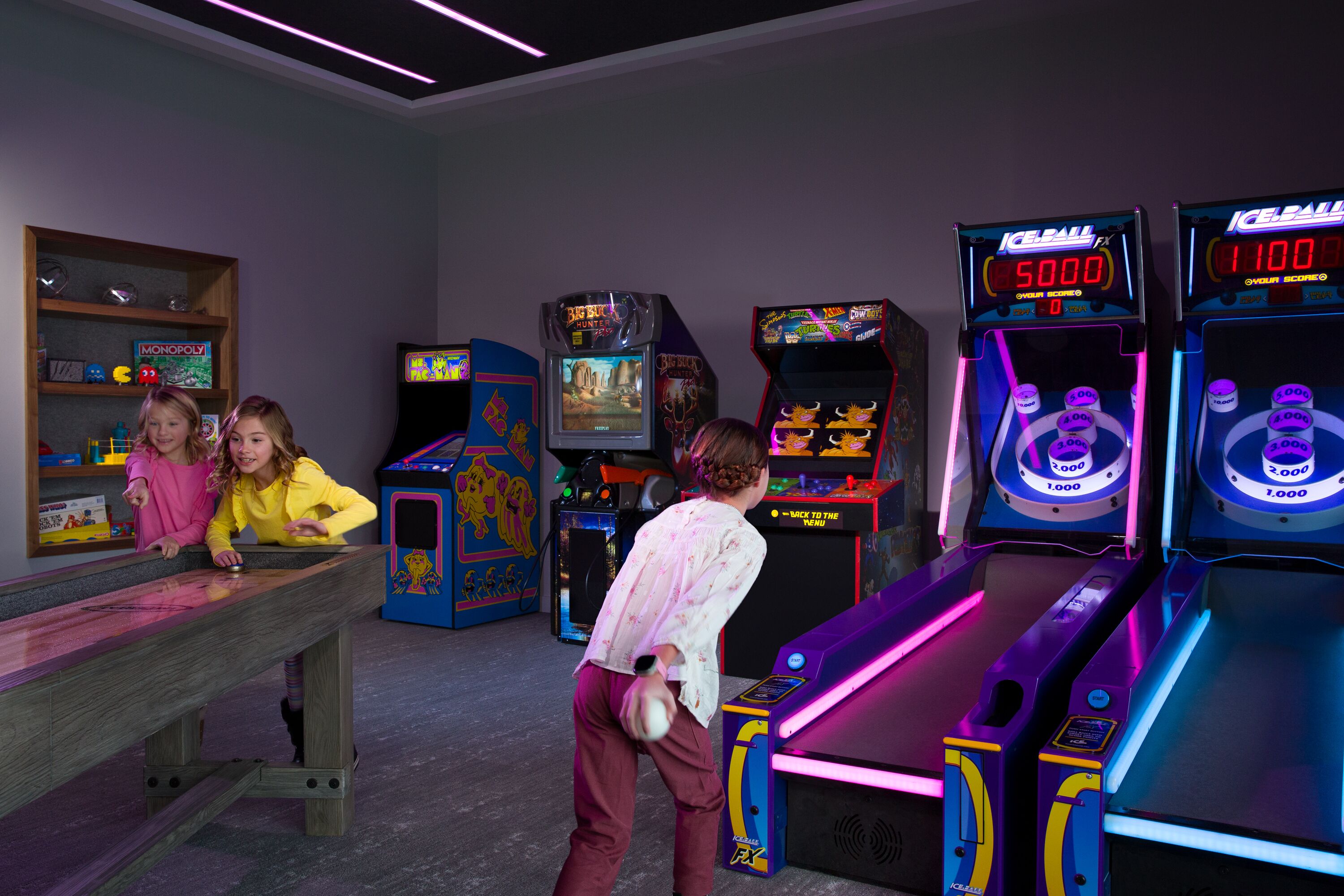 A room with arcade games, a wooden table, and shelves with board games.