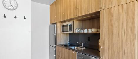 Una cocina moderna con armarios de madera, electrodomésticos de acero inoxidable y un reloj de pared.