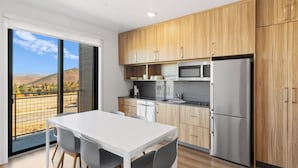 A modern kitchen with wooden cabinets, stainless steel appliances, and a white dining table with chairs.