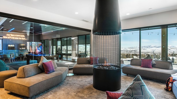 A modern living room with a fireplace, sofas, and a large window offering a view of the mountains.