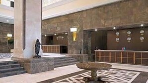A lobby with a reception desk, a statue, and a patterned floor. - Ramada Plaza Hotel (Astana)