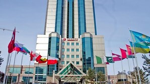 A modern building with the name "RAMADA" on the facade, surrounded by multiple national flags. - Ramada Plaza Hotel (Astana)