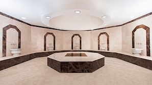 A spacious, modern bathroom with a central marble sink, multiple archways, and a circular ceiling design. - Ramada Plaza Hotel (Astana)
