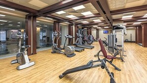 A gym with various cardio machines, weightlifting equipment, and a wooden floor. - Ramada Plaza Hotel (Astana)