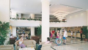 A spacious lobby with multiple seating areas, a reception desk, and a chandelier. - Palmin Hotel (Kuşadası)