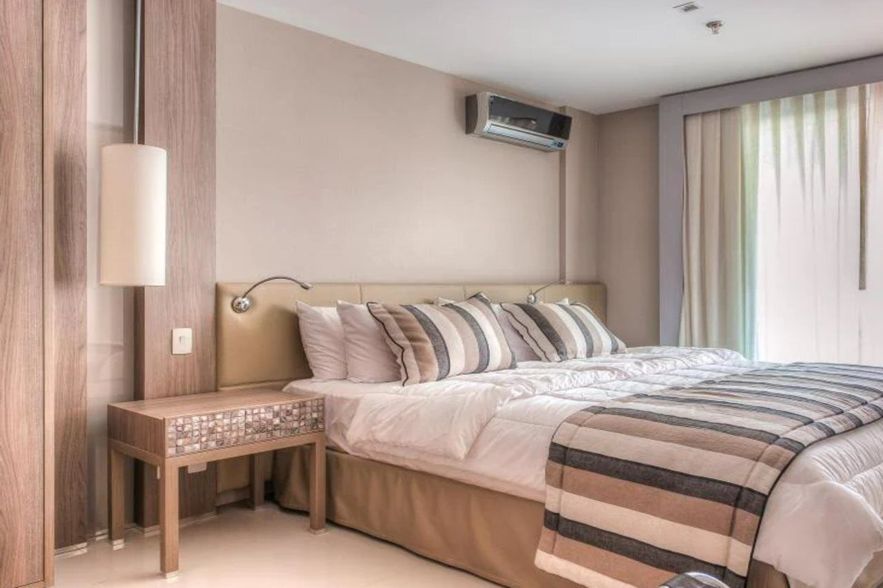 Quarto com cama, mesa de cabeceira e ar condicionado.