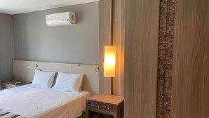Een hotelkamer met een bed, nachtkastje en een wandairconditioner.