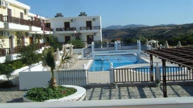 A hotel with a swimming pool, surrounded by a fenced area with a pergola and a view of the hills. - Anemoessa (Karpathos)