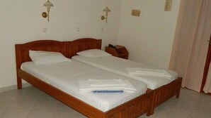 A double bed with a wooden frame, two bedside tables, and two wall-mounted lamps. - Anemoessa (Karpathos)