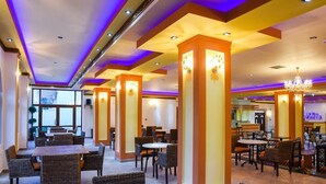 A spacious restaurant with high ceilings, modern lighting, and a variety of seating arrangements including tables and chairs. - Chrysoula (Kos)