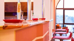 A kitchen counter with a lava lamp, red plates, and bar stools. - Chrysoula (Kos)