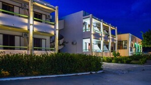 A modern hotel with multiple floors, balconies, and a well-lit exterior. - Chrysoula (Kos)