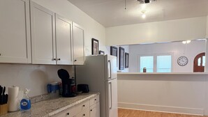 A kitchen with white cabinets, a granite countertop, a refrigerator, and a coffee maker. - Fully furnished duplex in quiet neighborhood (Sweetwater)