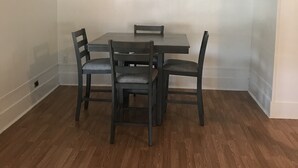 A dining area with a table and four chairs, a ceiling fan, and wooden flooring. - Fully furnished duplex in quiet neighborhood (Sweetwater)