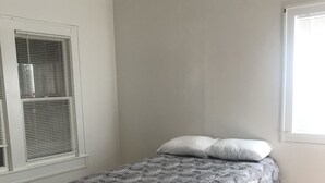 A bedroom with a bed, wooden flooring, a ceiling fan, and a window with blinds. - Fully furnished duplex in quiet neighborhood (Sweetwater)
