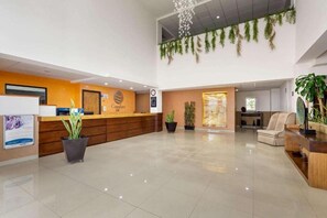 A hotel reception area with a wooden reception desk, a clock, and potted plants. - Comfort Inn Chihuahua, CHH (Chihuahua)
