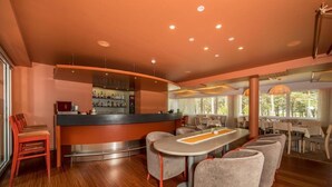 A modern bar area with a curved counter, seating with grey upholstered chairs, and a wooden floor. - Saarema Thalasso Spa Hotel (Mandjala)