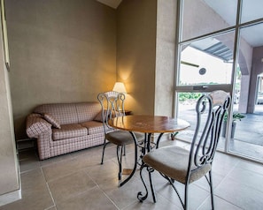 A room with a sofa, two chairs, a round table, and a lamp.