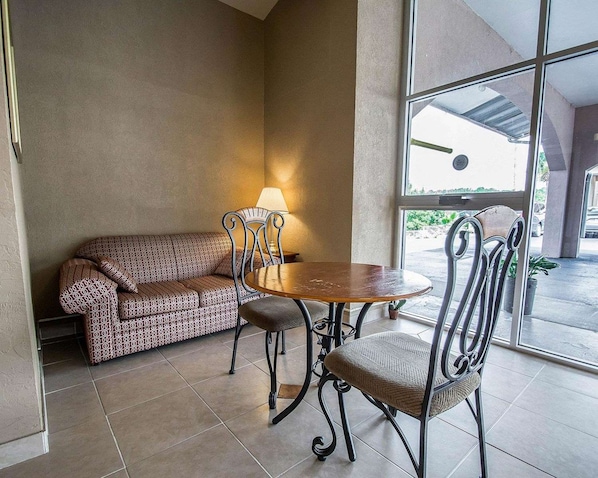 A room with a sofa, two chairs, a round table, and a lamp. - Rodeway Inn Gainesville University Area (Gainesville)