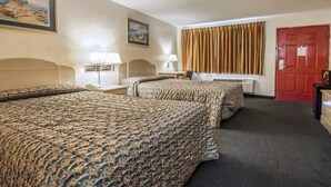 Habitación de hotel con dos camas, un escritorio, una silla, una lámpara, una puerta roja y una ventana con cortinas.