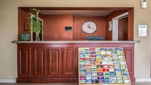 Una zona de recepción con mostrador de madera, un reloj, una planta y una exhibición de diversos juegos de cartas.