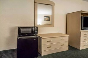 Una habitación compacta con kitchenette, que incluye refrigerador, microondas y un mueble bajo con cajones.