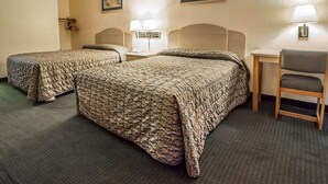 A hotel room with two beds, a desk, a chair, and two wall-mounted lamps.