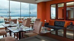 Ein modernes Hotelzimmer mit einem großen Fenster, das Blick auf Strand und Stadtpanorama bietet.