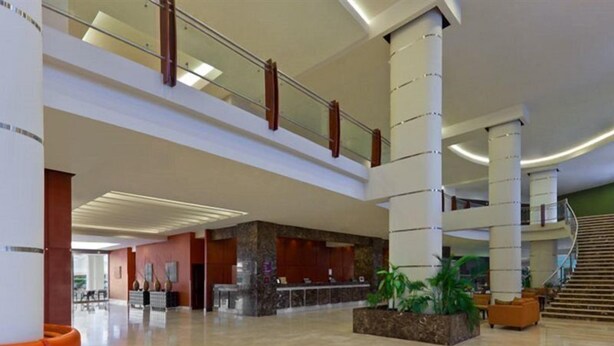 Eine großzügige Lobby mit Empfangsschalter, einer Treppe und einer Sitzecke.