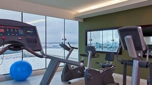 Ein Fitnessstudio mit Trainingsgeräten, großen Fenstern und Blick auf eine verschneite Landschaft.