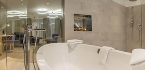 Une salle de bain moderne avec une grande baignoire, une douche en verre et une petite fenêtre avec des rideaux.