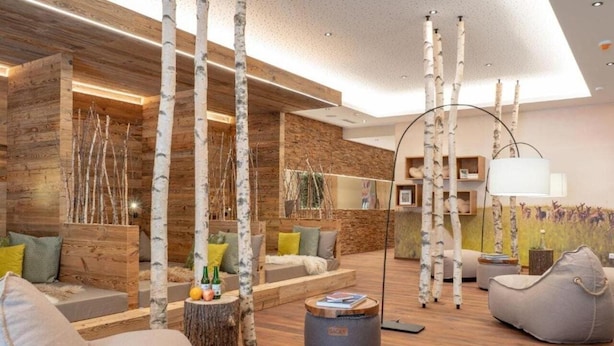 Una sala de estar moderna con paredes de madera, un sofá, una mesa de centro y adornos con ramas de abedul.