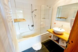 Een moderne badkamer met een bad, douche en wastafel.